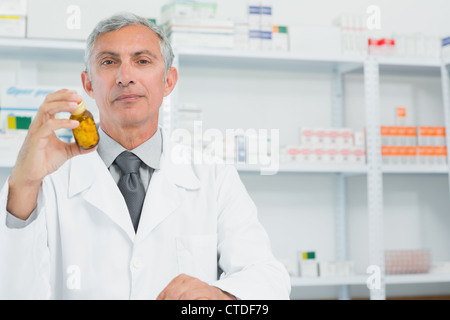 Serious pharmacist holding a bottle full of pills with one hand Stock Photo