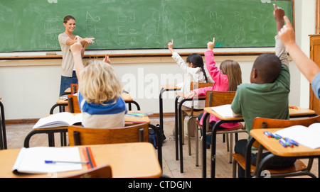 Back view of primary school class raising hands Stock Photo