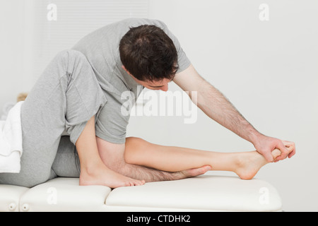 Brunette osteopath stretching a foot Stock Photo