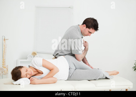 Chiropractor massaging the thigh of his patient while using his elbow Stock Photo