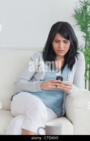 Woman using a phone while relaxing on a sofa Stock Photo