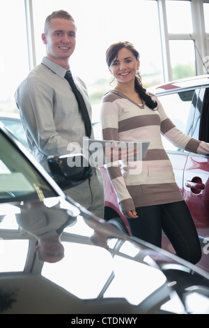 Salesman and a woman standing next to a car Stock Photo