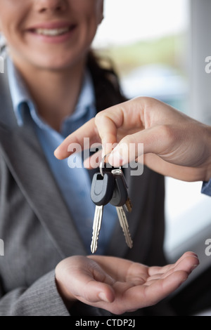 Hand holding keys over the hand of a woman Stock Photo