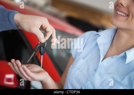 Smiling woman receiving keys from somebody Stock Photo