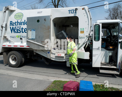 Garbage man loading Rethink Waste truck recycle bin lorry with household recycled paper in the Canadian town of Fort Erie Ontario Canada Stock Photo