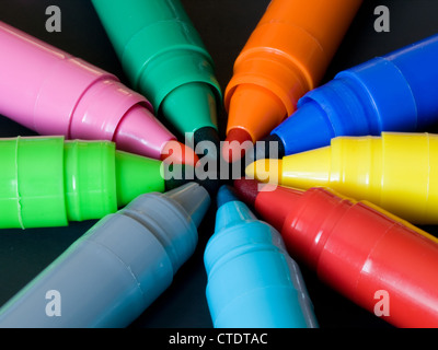 Several colored felt pens with caps off forming a circle on black background Stock Photo