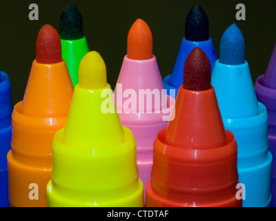 Several colored felt pens standing with caps off isolated on black background. Stock Photo