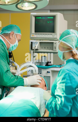 Patient lying on an operating table with two surgeons Stock Photo
