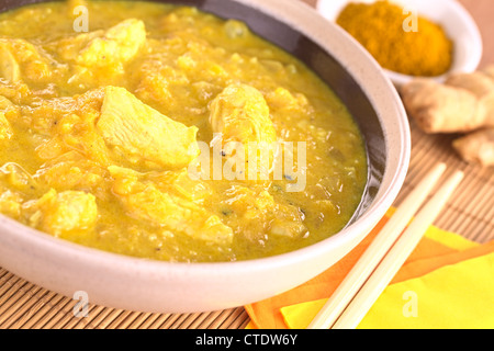 Indian chicken-mango curry dish in bowl with curry powder and ginger root in the back Stock Photo