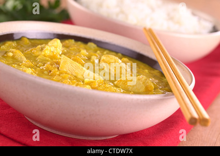 Chicken-mango curry with rice in the back (Selective Focus, Focus on the chicken pieces in the front) Stock Photo