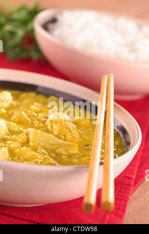Chicken-mango curry with rice in the back (Selective Focus, Focus on the chicken one third into the bowl) Stock Photo