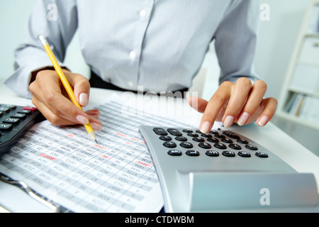 Photo of hands making notes with pencil and pressing calculator buttons Stock Photo