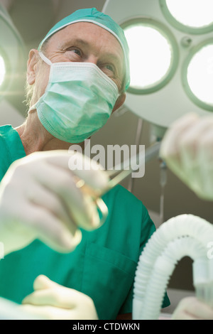 Surgeon smiles as he takes a surgical scissors Stock Photo