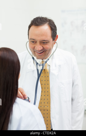 Smiling doctor auscultating a woman Stock Photo