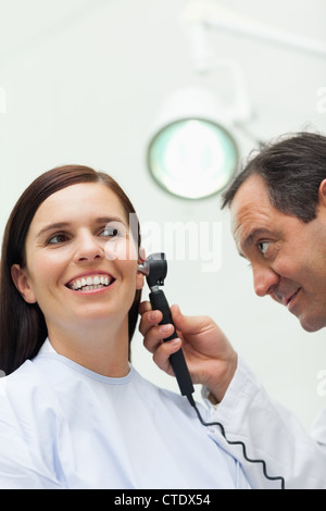 Doctor using an otoscope to look at the ear of a patient Stock Photo