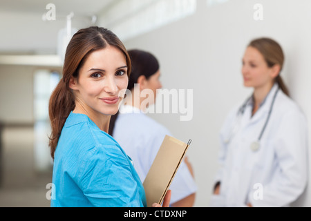 Nurse in a hallway with a doctor and a patient while holding files