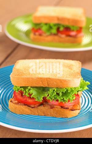 Fresh homemade BLT (bacon lettuce and tomato) sandwich on colorful plates Stock Photo
