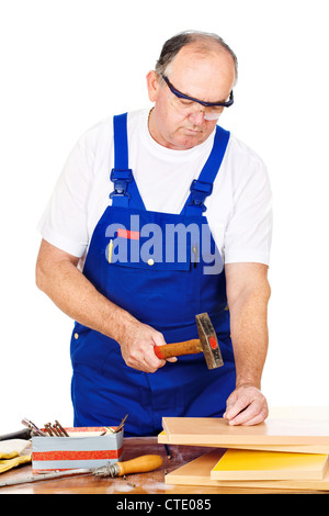 Middle age worker hammering nails in board, isolated on white background Stock Photo