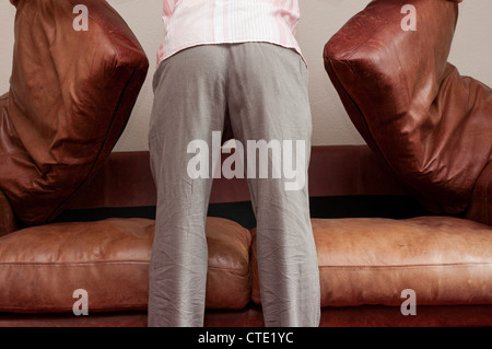 Man searching under sofa cushions for lost items. Stock Photo