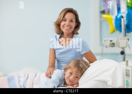 Child lying on a medical bed next to his mother Stock Photo