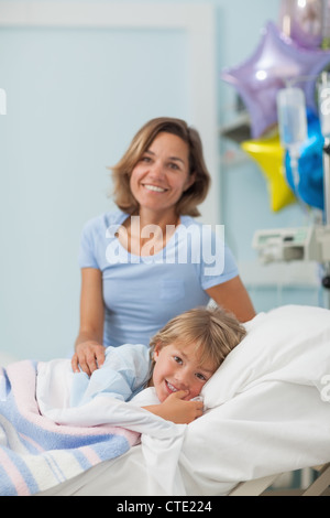 Child lying on a bed next to his mother Stock Photo