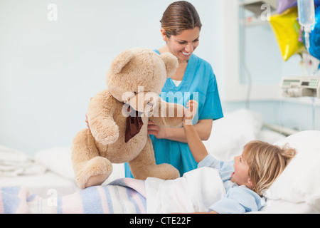 Nurse showing a teddy bear to a child Stock Photo