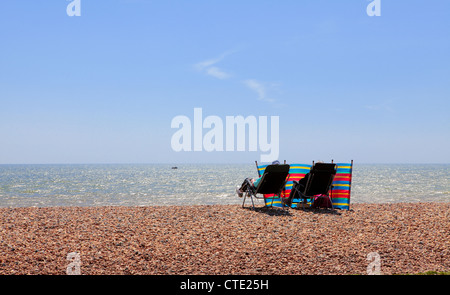 Two people sitting in deckchairs on a beach Stock Photo