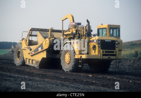 A Caterpillar-631G Land Scraper Vehicle journeying upon a land reclamation-site to return wasteland into an open public park. Stock Photo
