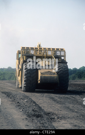 A Caterpillar-631G Land Scraper Vehicle journeying upon a land reclamation-site to return wasteland into an open public park. Stock Photo