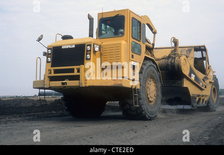 A Caterpillar-631G Land Scraper Vehicle Journeying upon a land reclamation-site to return wasteland into a open public park. Stock Photo