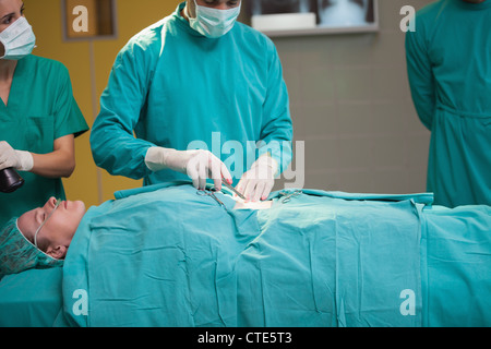 Surgeon opening the belly of a patient Stock Photo