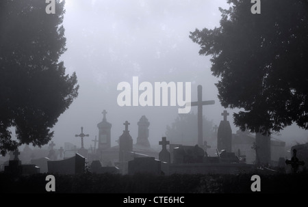 Eerie silhouetted tombstones, grisly graves and creepy crosses at ghastly graveyard with trees in foggy mist atmosphere