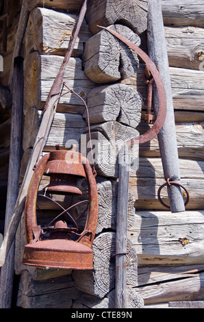 rusty sickle and kerosene lamp on old farm wooden wall Stock Photo