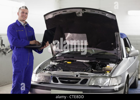 Mechanic typing on a computer while looking at camera Stock Photo