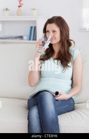Woman drinking while sitting on a sofa Stock Photo