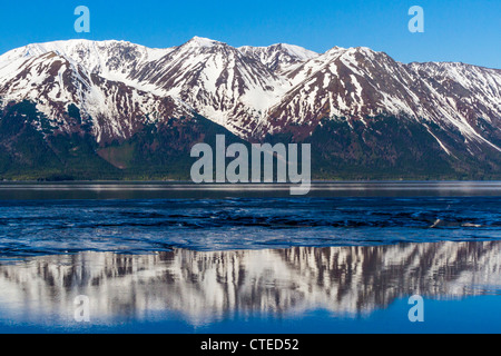 Reflections of snow-covered mountains in beautiful blue waters of 'Turnagain Arm,' an arm of 'Cook Inlet' in Alaska. Stock Photo
