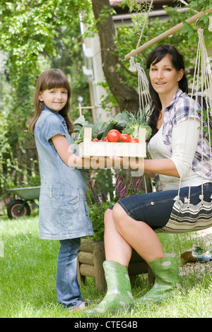 Mother with daughter looking at fresh veggies in the garden Stock Photo