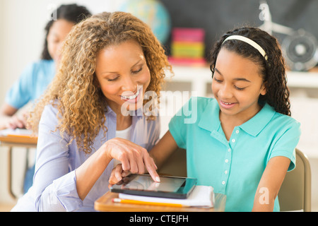 USA, New Jersey, Jersey City, Schoolgirls (10-13) using tablet pc, assisted by teacher Stock Photo