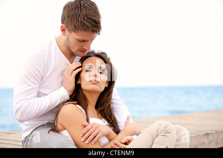 Portrait of a romantic couple sitting together on a pier Stock Photo