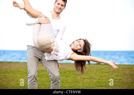 Portrait of a romantic young couple enjoying and having fun at a windy beach Stock Photo