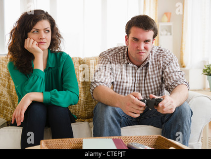 USA, New Jersey, Jersey City, Couple sitting on sofa, man playing video game Stock Photo