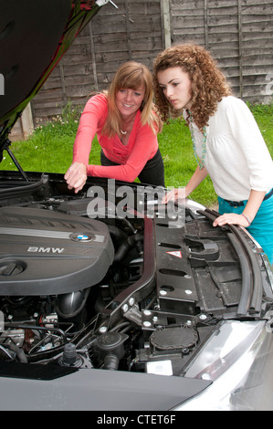 Young driver learning the workings in the engine compartment of a car Stock Photo