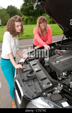 Young driver learning the workings in the engine compartment of a car Stock Photo