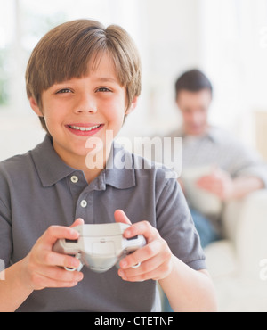 USA, New Jersey, Jersey City, Boy (10-11 years) playing video game with father sitting in background Stock Photo