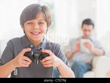 USA, New Jersey, Jersey City, Boy (10-11 years) playing video game with father sitting in background Stock Photo