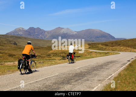 Two cyclists cycling on a quiet country road towards An Teallach in northwest highlands Dundonnell Wester Ross Ross and Cromarty Highland Scotland UK Stock Photo