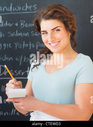 USA, New Jersey, Jersey City, Portrait of smiling waitress against blackboard with menu Stock Photo