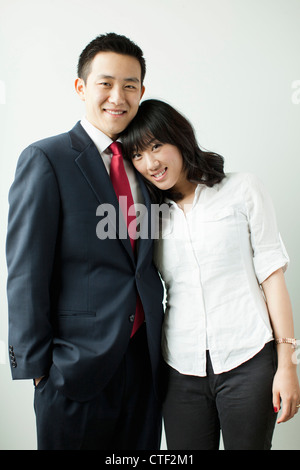studio portrait of young asian couple, standing back to back, looking ...