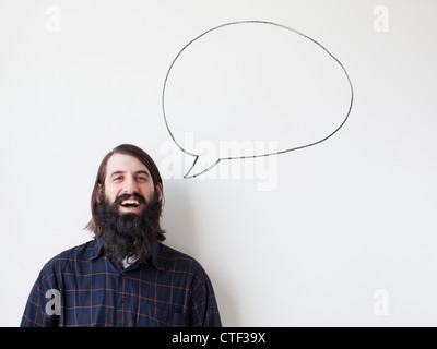Bearded young man standing next to speech bubble on white background Stock Photo