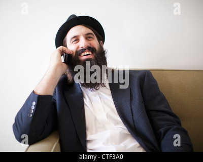 Happy bearded young man sitting on sofa Stock Photo